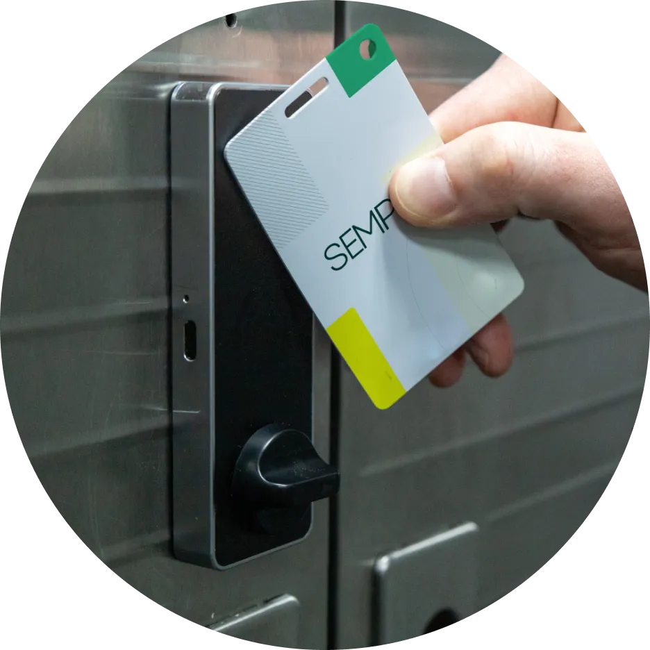 A hand tapping a Sempro keycard against an electronic lock